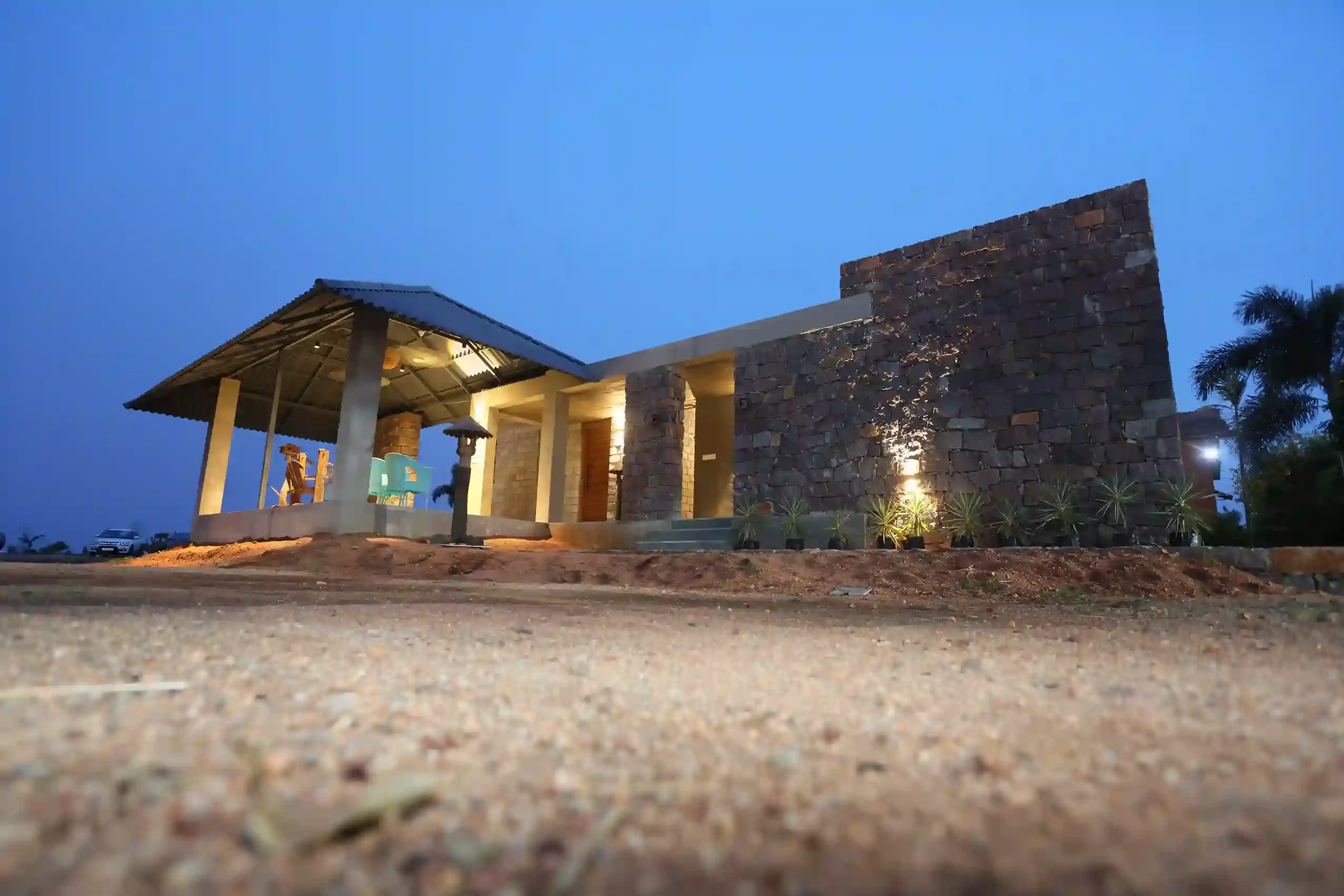 A modern stone farmhouse illuminated at dusk.